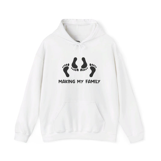 White hoodie with "Making My Family" design, featuring footprints for a sarcastic adult humor twist. Perfect for men who enjoy witty apparel.