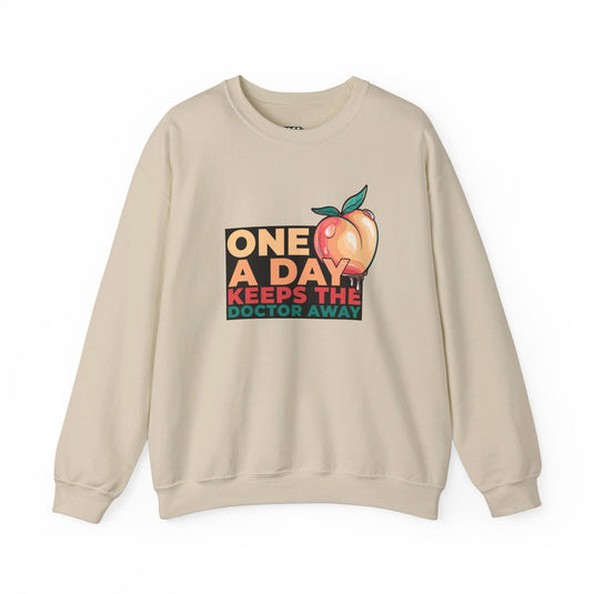 Sand-colored sweatshirt with a playful "One a Day Keeps the Doctor Away" design and a peach, great for men and women with a sense of humor.