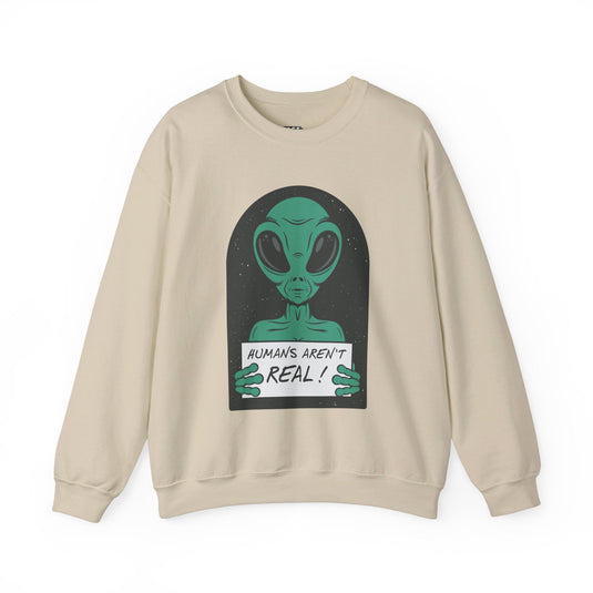 Sand-colored sweatshirt featuring a funny alien holding a sign that says "Humans Aren't Real!" in a sarcastic manner.